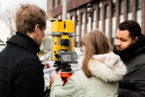 cursist maakt gebruik van total station om een meeting te doen tijdens de leergang landmeetkunde